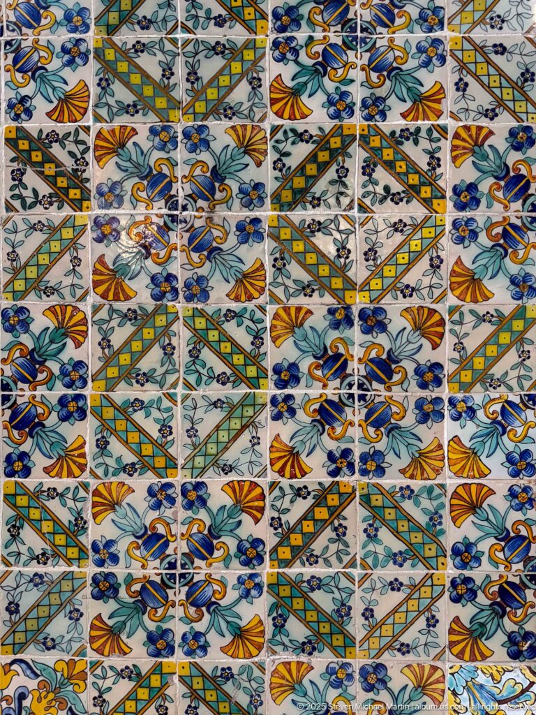 Close-up of multicolored ceramic tiles with repeating floral motifs, curling leaves, and diagonal geometric bands.