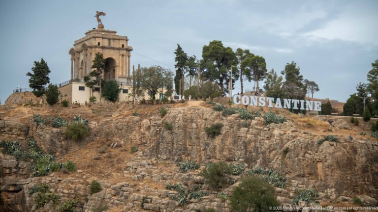 Constantine’s Monument aux Morts on a rocky hill beside large white letters spelling CONSTANTINE.