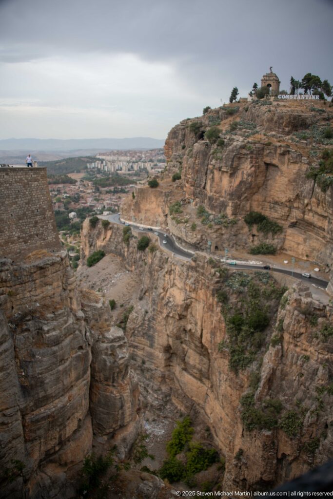 Wide view across Constantine’s rocky gorge to a cliff road, plateau, and distant valley.