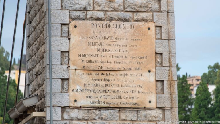Inscribed plaque on stone masonry headed “PONT DE SIDI M’CID,” listing officials and engineers.