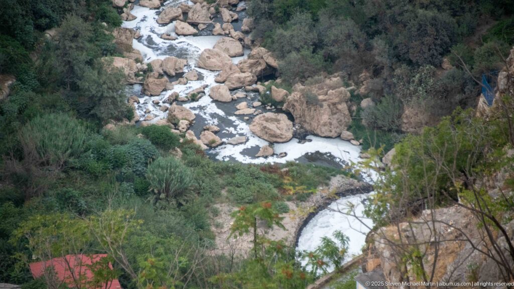 Rhumel River winding among pale boulders and dense vegetation at the bottom of Constantine’s steep gorge.