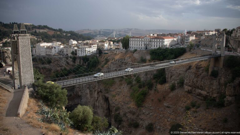 Elevated view of Sidi M’Cid Bridge carrying vehicles across Constantine’s deep rocky gorge between urban cliffs.