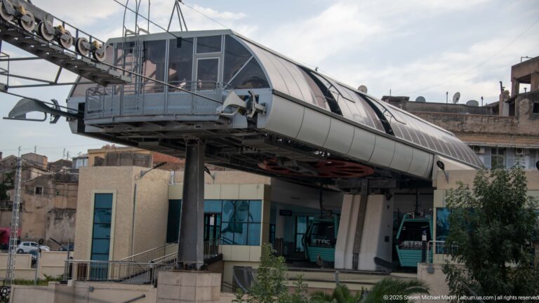 Modern Constantine cable-car station with curved canopy and enclosed gondola cabins beneath the platform.