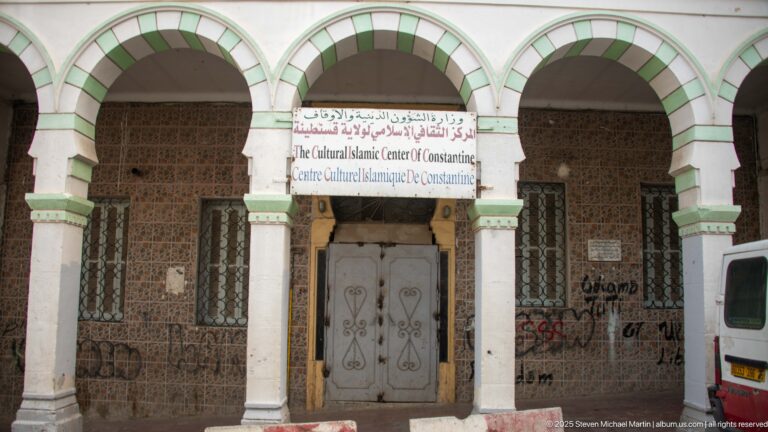Entrance to the Cultural Islamic Center of Constantine beneath green-and-white arches and a bilingual sign.