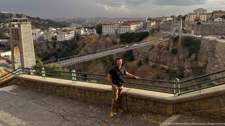 Man at a viewpoint above Constantine’s gorge with Sidi M’Cid Bridge and city buildings behind him.