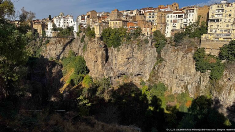 Dense pale buildings and red roofs perched along the sunlit edge of Constantine’s sheer rocky gorge.