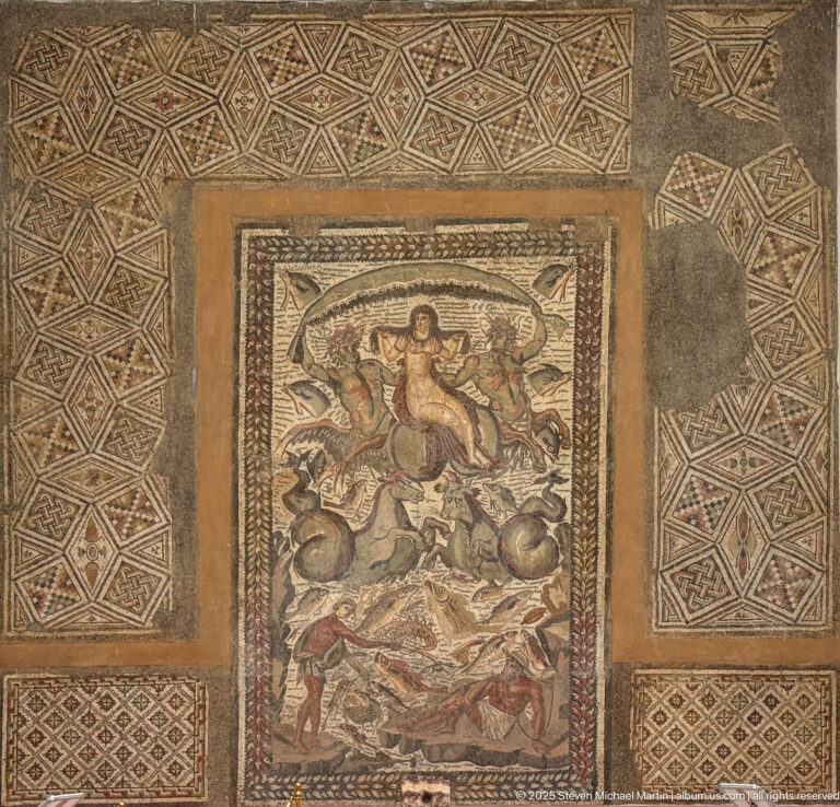 Wide view of the Triumph of Venus mosaic set within a large geometric pavement of lozenges and interlaced patterns.