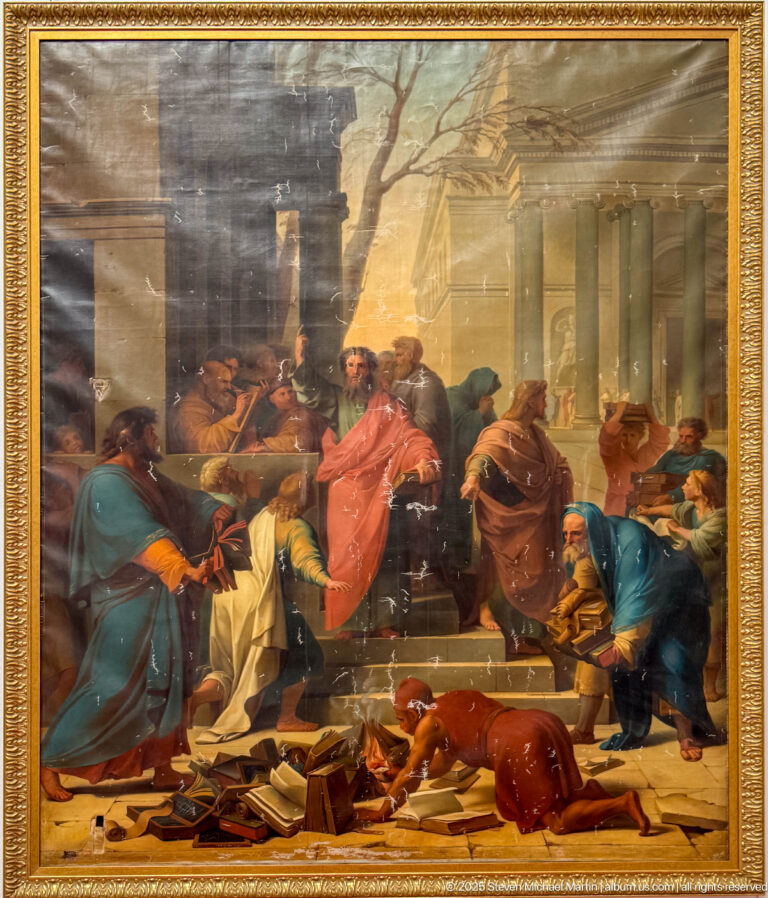 Large framed history painting of robed figures around a central man in red, with columns and scattered books in front.
