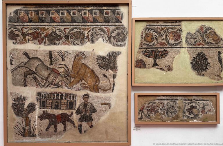 Mounted mosaic fragments with animals, plants, a building, decorative borders, and a standing human figure.