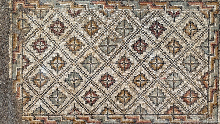 Rectangular mosaic with a repeating diamond lattice, small colored motifs, and a patterned border.