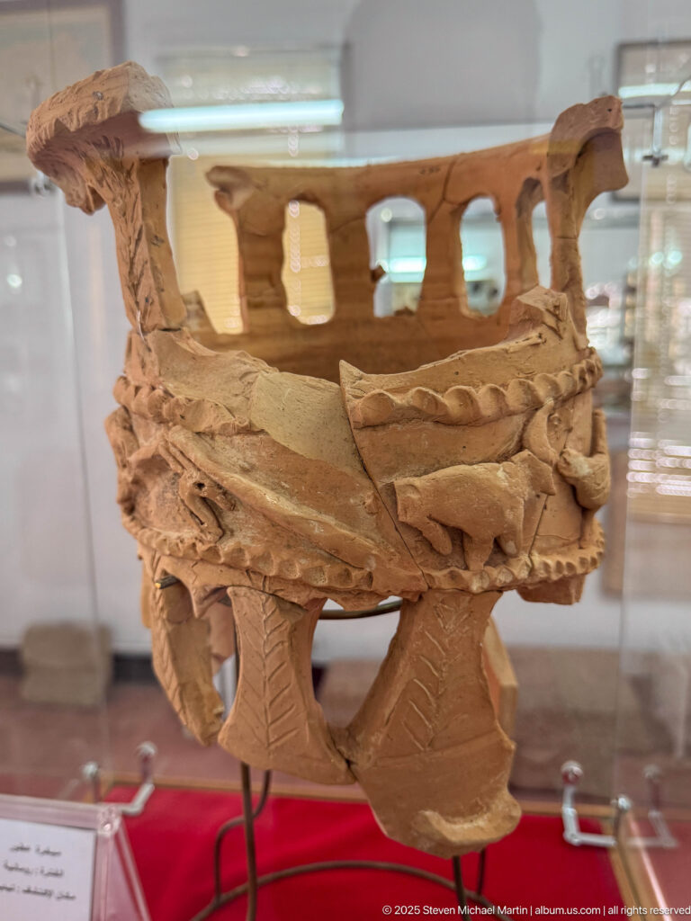 Fragmentary terracotta openwork structure with arched openings, high rim, and applied geometric decoration.
