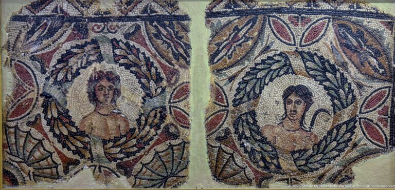 Two female mosaic portrait busts side by side, each framed by a leafy wreath and red decorative motifs.