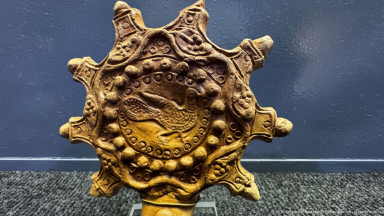 Star-shaped ornate metal object with a raised circular center, beaded borders, scrolls, and projecting points.