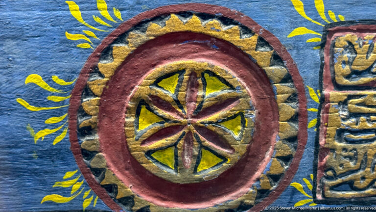 Close-up of a circular red, yellow, and blue medallion with an eight-part radial floral design.
