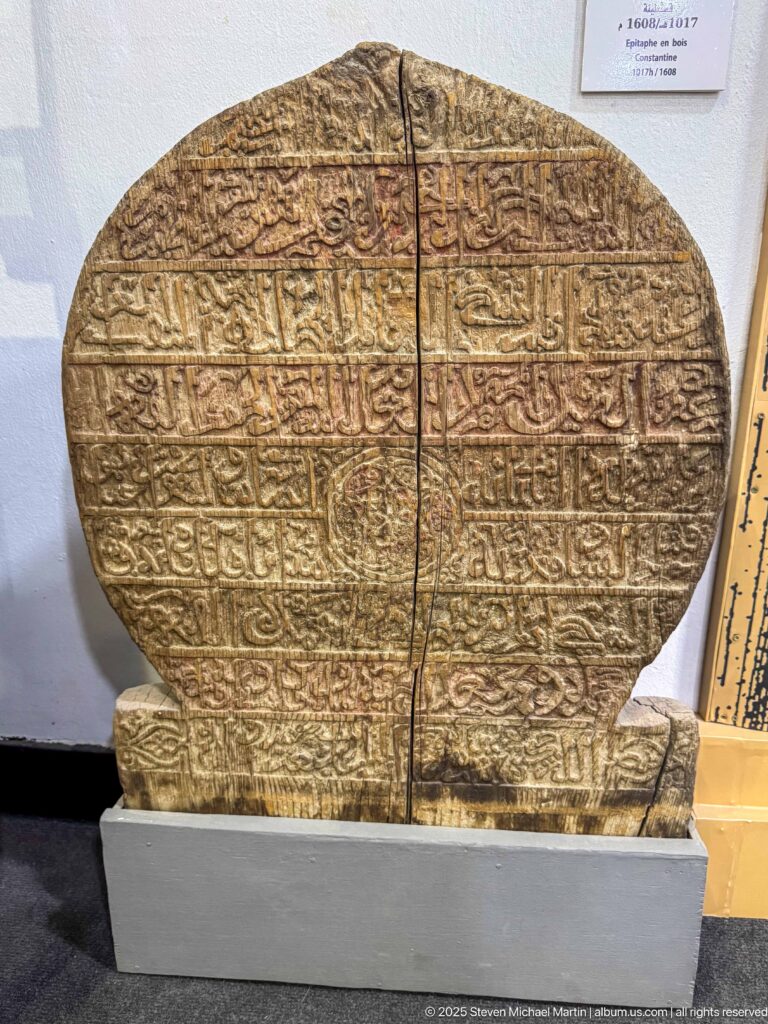 Large rounded stone slab covered in carved Arabic script, split vertically into two principal pieces.