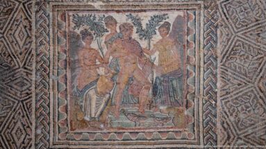 Figurative Roman mosaic with a standing man surrounded by several women, framed by dense interlaced geometric borders.