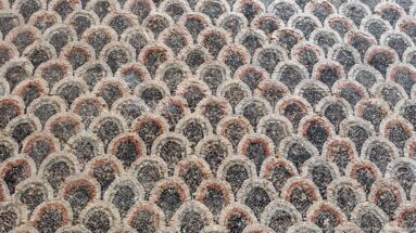 Close Roman mosaic detail of overlapping cream scallops outlined in black with red-brown centers.