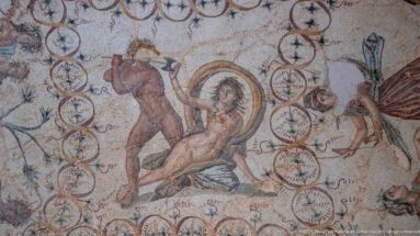 Central scene of the Djemila Bacchus Mosaic with a standing attacker and reclining figure inside a ring of circular motifs.