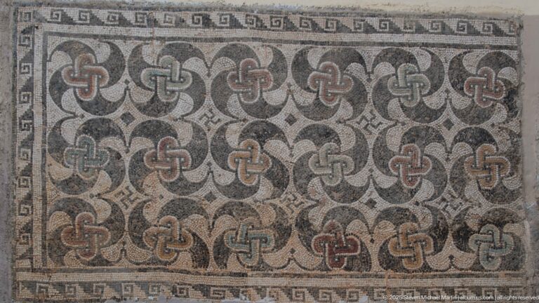 Roman mosaic panel filled with interlaced quatrefoil motifs in gray, cream, black, and muted red, edged by a meander border.