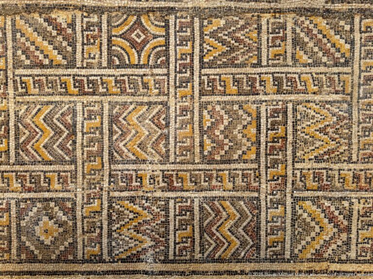 Close Roman mosaic detail with rectangular compartments of zigzags, diamonds, stepped forms, and meander-like borders.