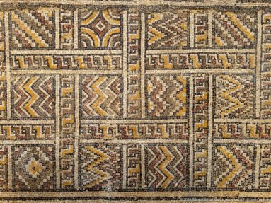 Close Roman mosaic detail with rectangular compartments of zigzags, diamonds, stepped forms, and meander-like borders.