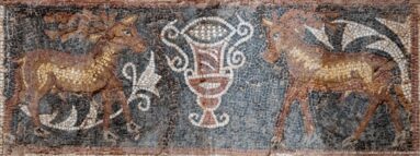 Roman mosaic with two slender hoofed animals facing a tall central vessel amid dark scrolling foliage.