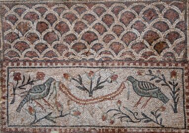 Roman mosaic with two facing birds, flowering branches, and a beaded garland below a scalloped geometric border.