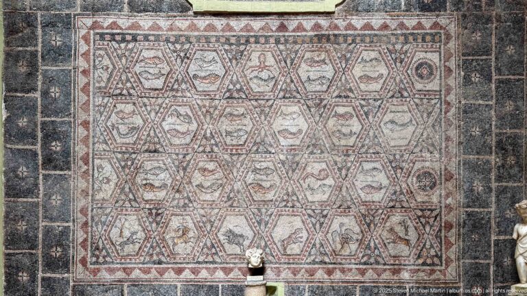 Large Roman mosaic of hexagonal compartments containing vessels, animals, birds, and small decorative emblems.