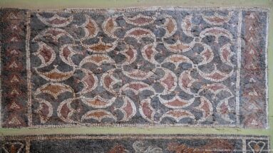 Roman mosaic with interlocking circular bands forming petal-like shapes in red, cream, black, and gray.