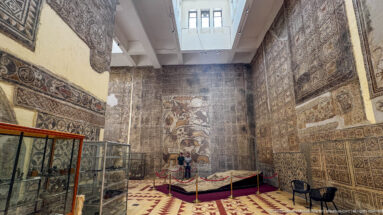 Skylit Djemila Museum gallery with the Great Hunt Mosaic at the far wall amid extensive Roman mosaics.