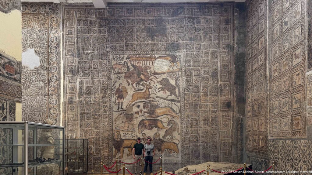 Frontal museum view of the Great Hunt Mosaic from the House of Bacchus surrounded by geometric mosaics.