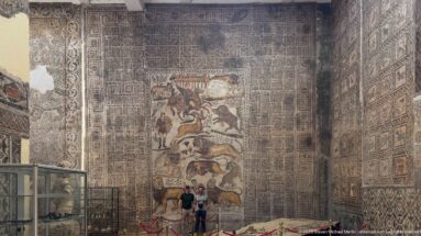Frontal museum view of the Great Hunt Mosaic from the House of Bacchus surrounded by geometric mosaics.