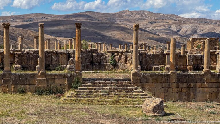 Stone steps leading to a raised Roman terrace with standing columns and low walls at Djemila.