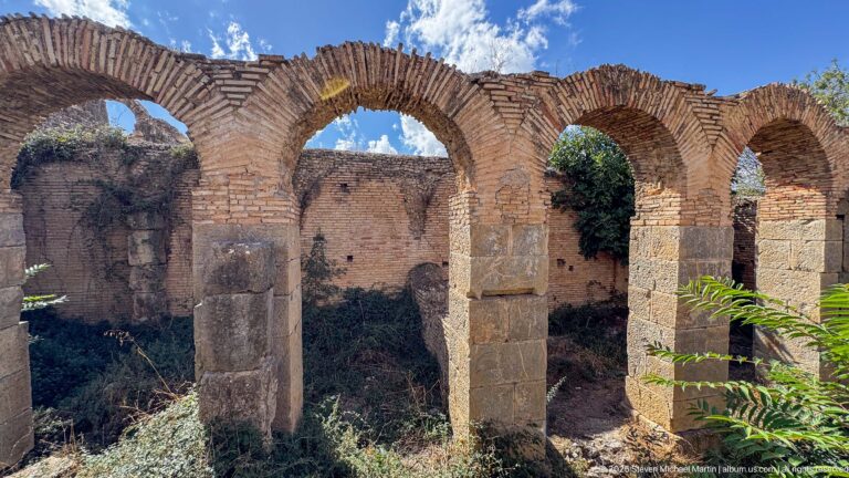 Row of broad Roman brick arches on masonry piers inside a roofless ruined structure at Djemila.
