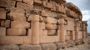 Two engaged columns and large stone panels on the Medracen, beneath irregular weathered and displaced upper masonry.