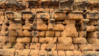 Close view of engaged column forms and large weathered stone blocks on the lower exterior wall of the Medracen.