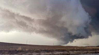Dark storm cloud with a narrow funnel-like lowering over open plateau terrain near Timgad.