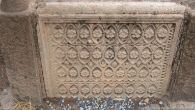 Rectangular stone panel carved with a repeating lattice of almond-shaped compartments and small floral motifs.