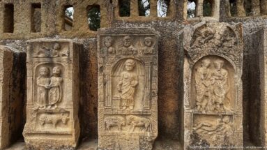 Three weathered stone stelae with carved human figures, busts, animals, and architectural framing.