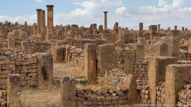 Dense Roman masonry foundations, wall stubs, and scattered columns across the ruins of Timgad.