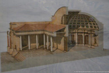Architectural reconstruction model with a columned entrance and cutaway domed interior.
