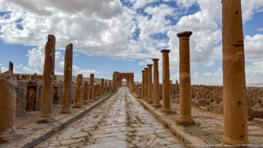 Long paved colonnaded street leading directly toward the Arch of Trajan at Timgad.
