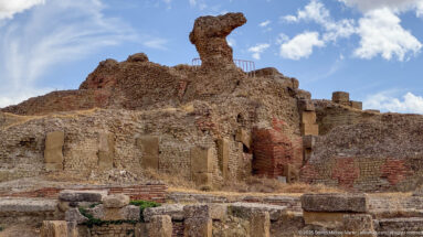 Large Roman brick-and-rubble ruins with surviving openings and layered wall masses at Timgad.