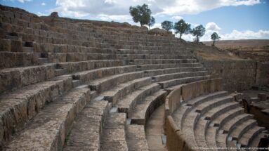 Close oblique view of curving stone seating tiers and radial steps in Timgad’s Roman theater.