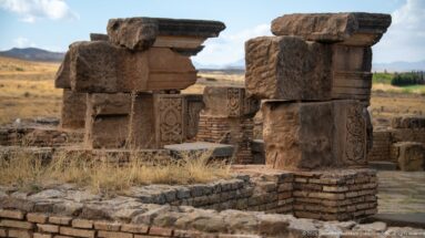 Heavy stone piers framing carved panels and brick masonry within the ruins of Timgad.