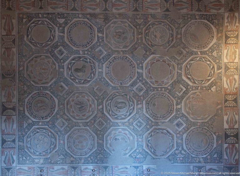 Large wall-mounted mosaic panel with rows of circular and polygonal medallions, each containing varied geometric motifs.