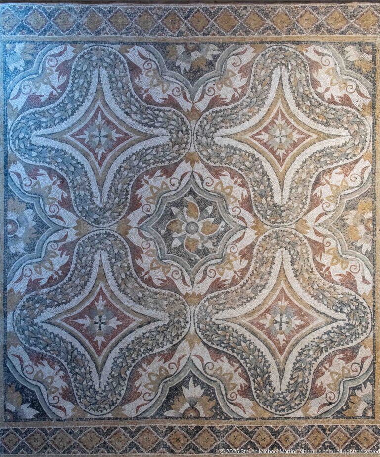 Polychrome mosaic pavement with interlocking lozenge forms, star centers, and linked geometric bands.