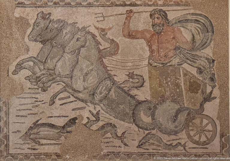 Neptune brandishing a trident while driving a four-horse sea chariot through fish and marine creatures in a Roman mosaic from Timgad.