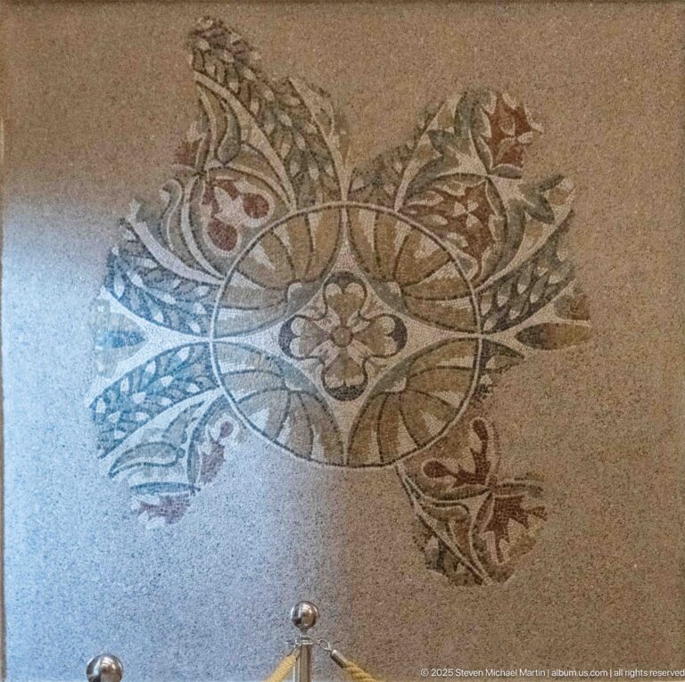 Small Roman mosaic fragment with a circular arrangement of leaves, buds, and a central flower.