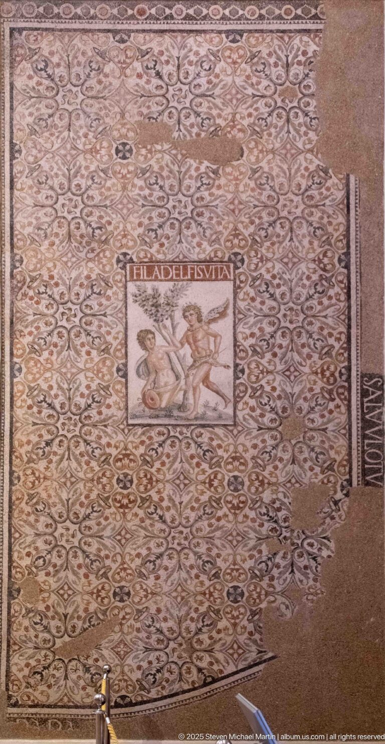 Mosaic of the Philadelphi with dense ornament, FILADELFIS VITA inscription, and central scene of Zeus as a satyr pursuing Antiope.